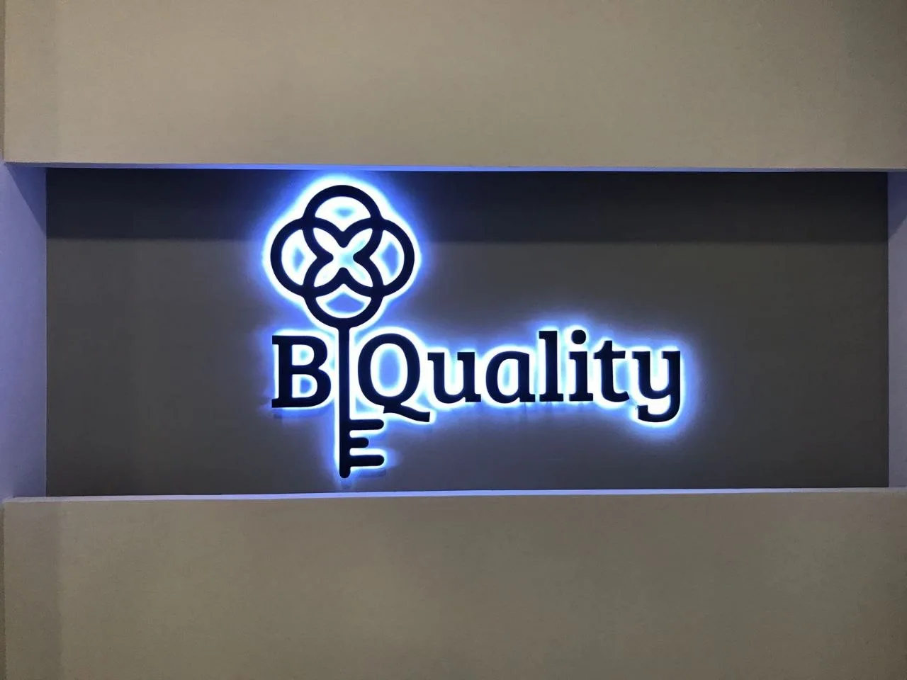 The B Quality interior sign in Barcelona: black 3D letters with a key logo and cool halo lighting on a dark panel