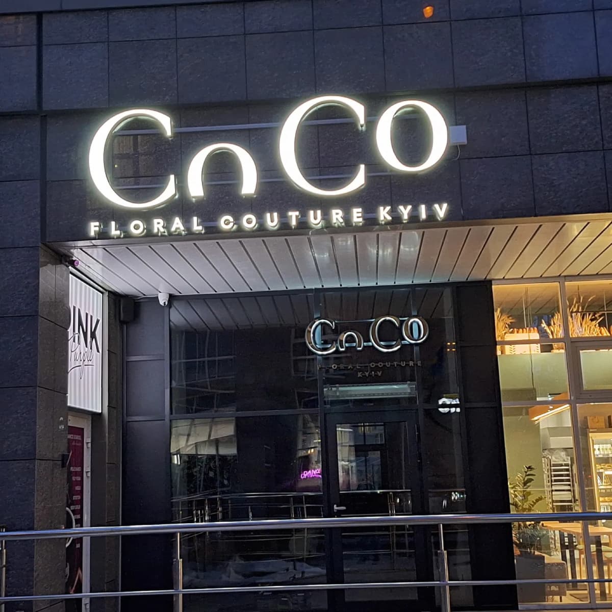 Pale halo-lit CoCo Floral Couture Kyiv letters above the boutique entrance at night