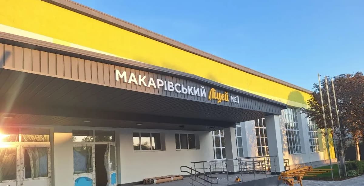Dimensional letters in white and yellow spelling out the Makariv lyceum’s name on the dark sloping fascia above the school entrance