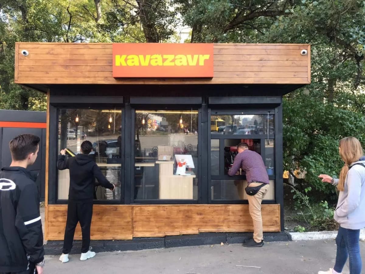 Timber kavazavr coffee kiosk with a red fascia sign being installed