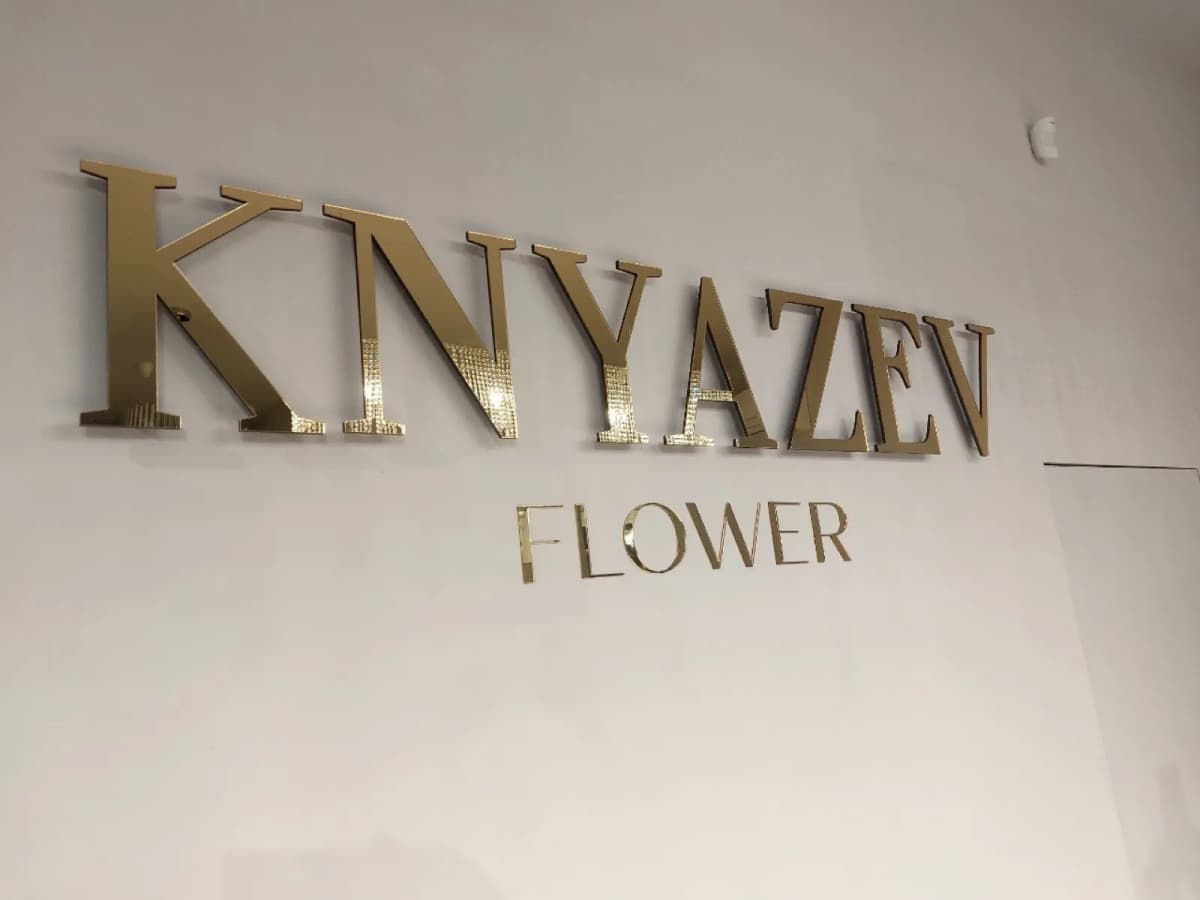 Gold 3D KNYAZEV FLOWER letters on the pale wall of a flower studio
