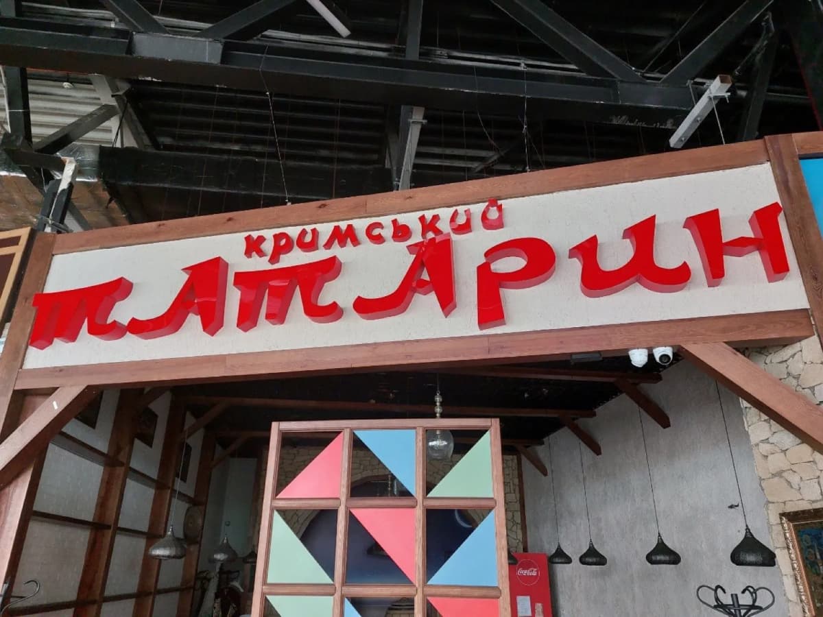 Red 3D-letter sign “кримський ТАТАРИН” over a restaurant entrance
