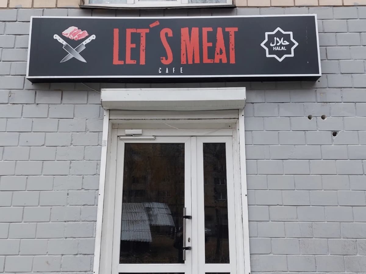 Black LET’S MEAT cafe lightbox with red lettering and a halal mark above the entrance
