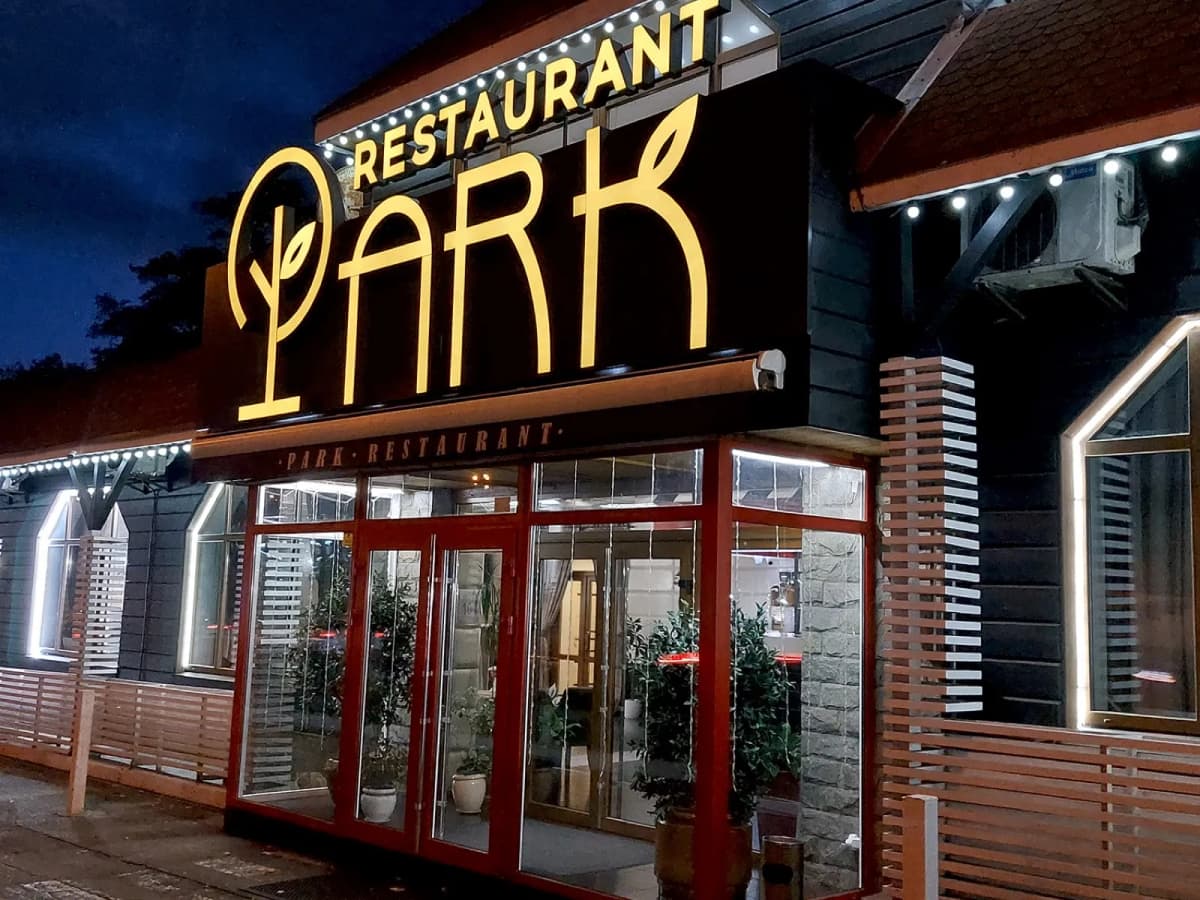 Illuminated PARK Restaurant sign with warm 3D letters above the restaurant entrance at night