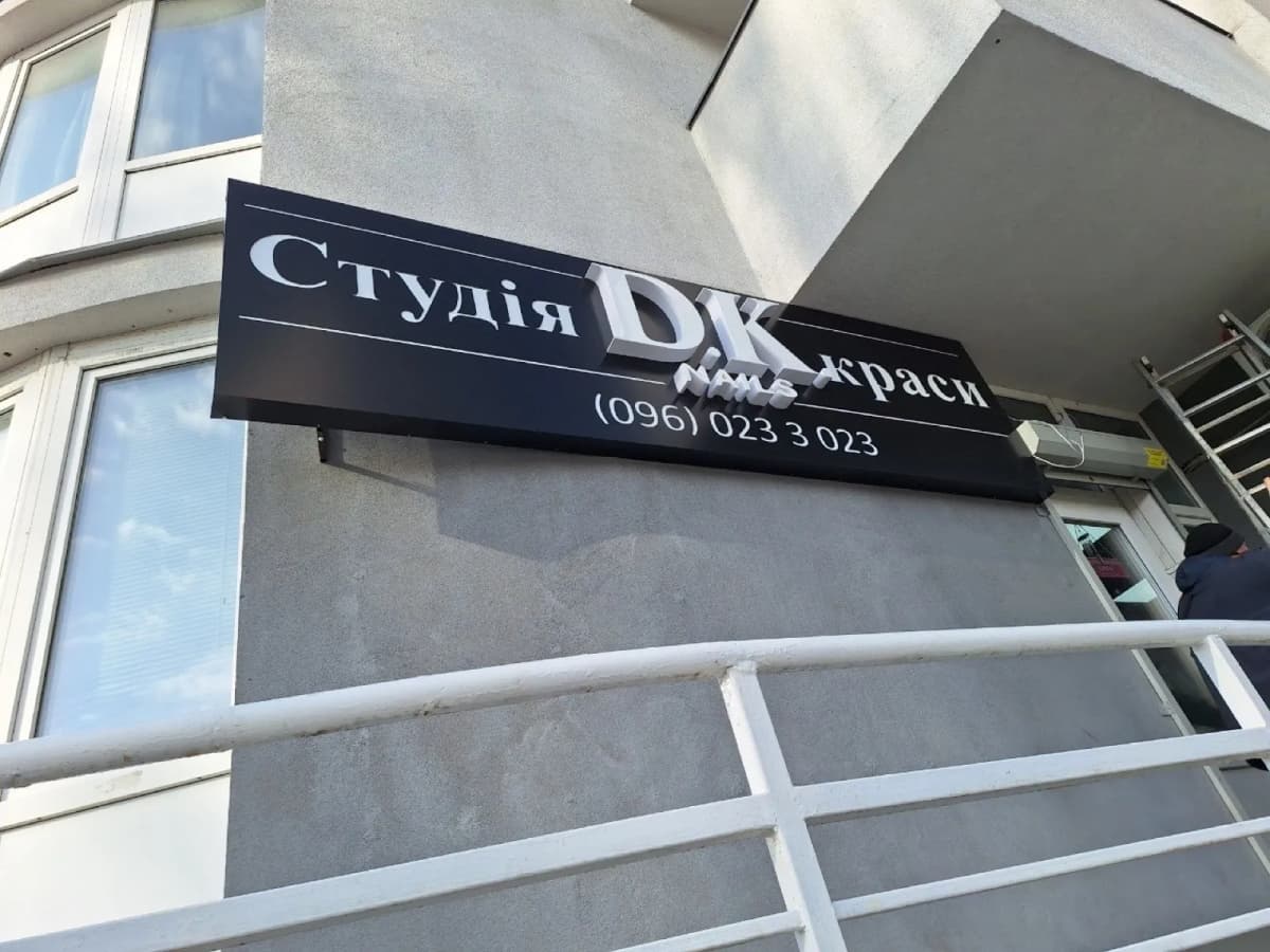 Black lightbox sign “Студія DK краси” on a beauty-salon facade