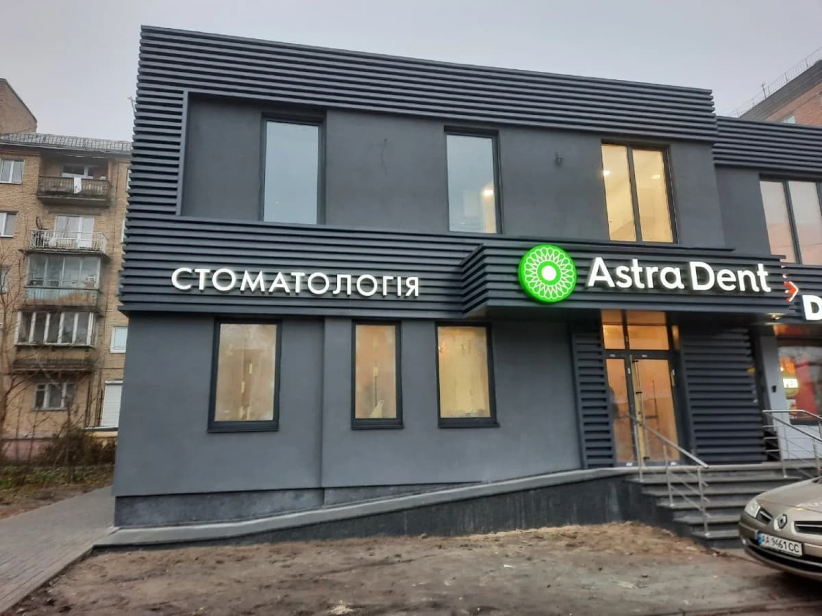 Astra Dent clinic facade with an illuminated dentistry sign and logo